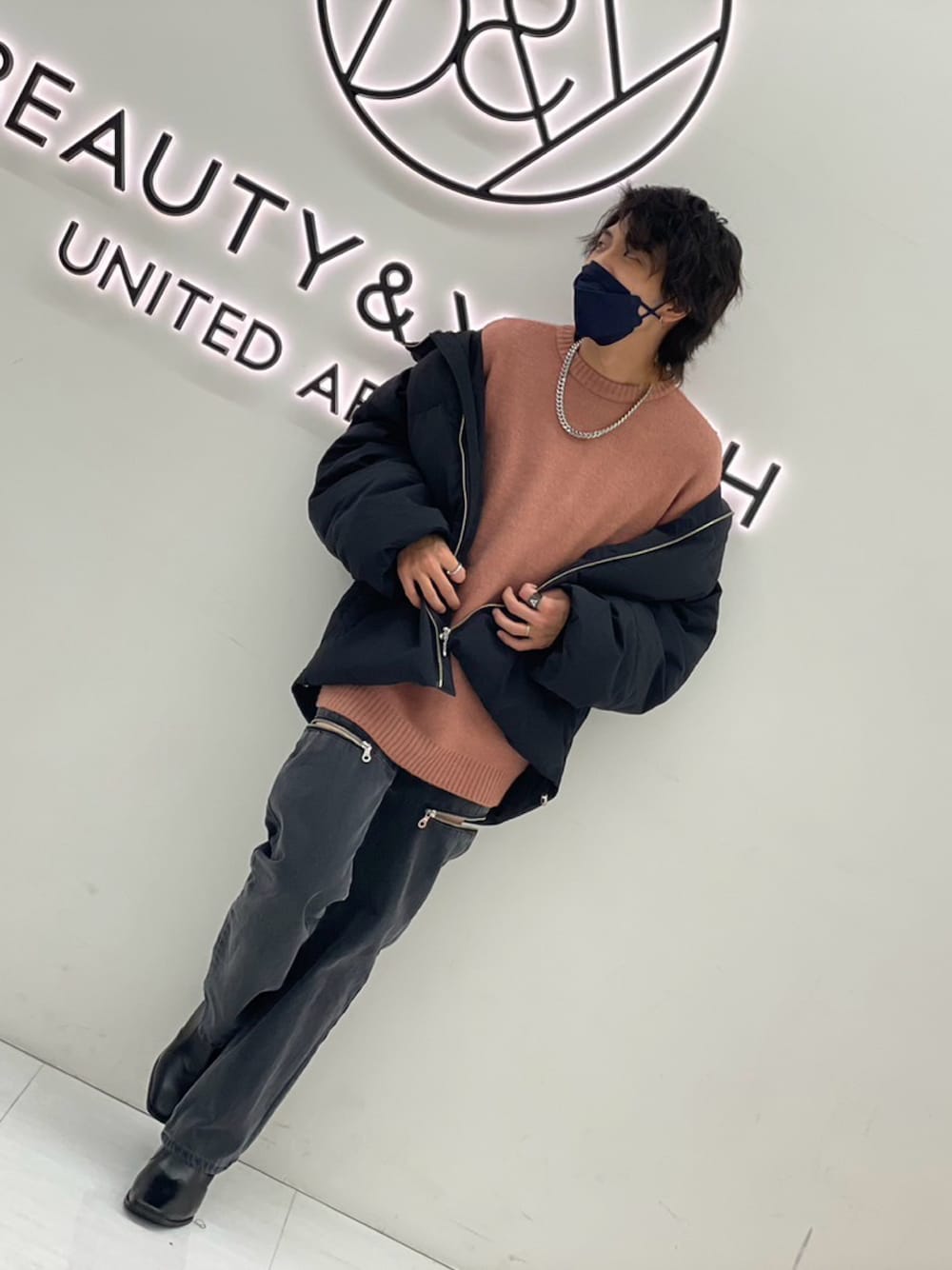 ブラック系のダウンジャケット/コート、グレー系のデニムパンツ、ピンク系のニット/セーターを着用したメンズの冬コーディネートの1枚目の写真