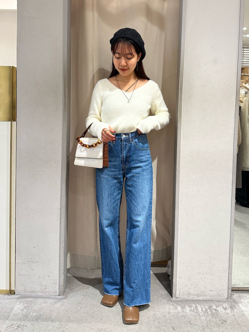 ブルー系のデニムパンツ、ブラウン系のブーツを着用したレディースの秋コーディネートの1枚目の写真