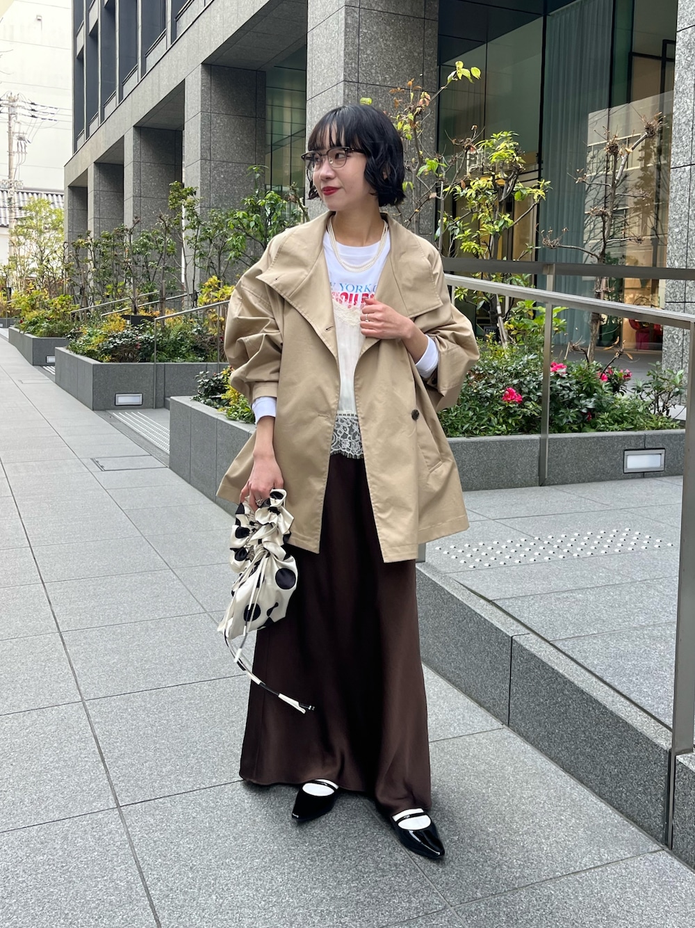 ホワイト系のキャミソール、ベージュ系のトレンチコート、ホワイト系のTシャツ/カットソーを着用したレディースの冬コーディネートの1枚目の写真