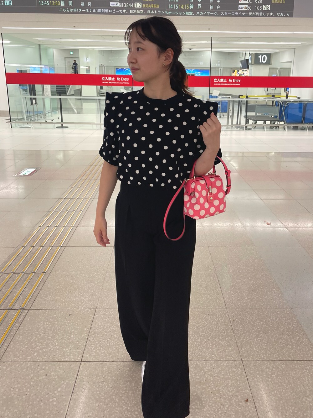 ブラック系のトップス、ブラック系のパンツ、ホワイト系のスニーカーを着用したレディースの夏コーディネートの1枚目の写真