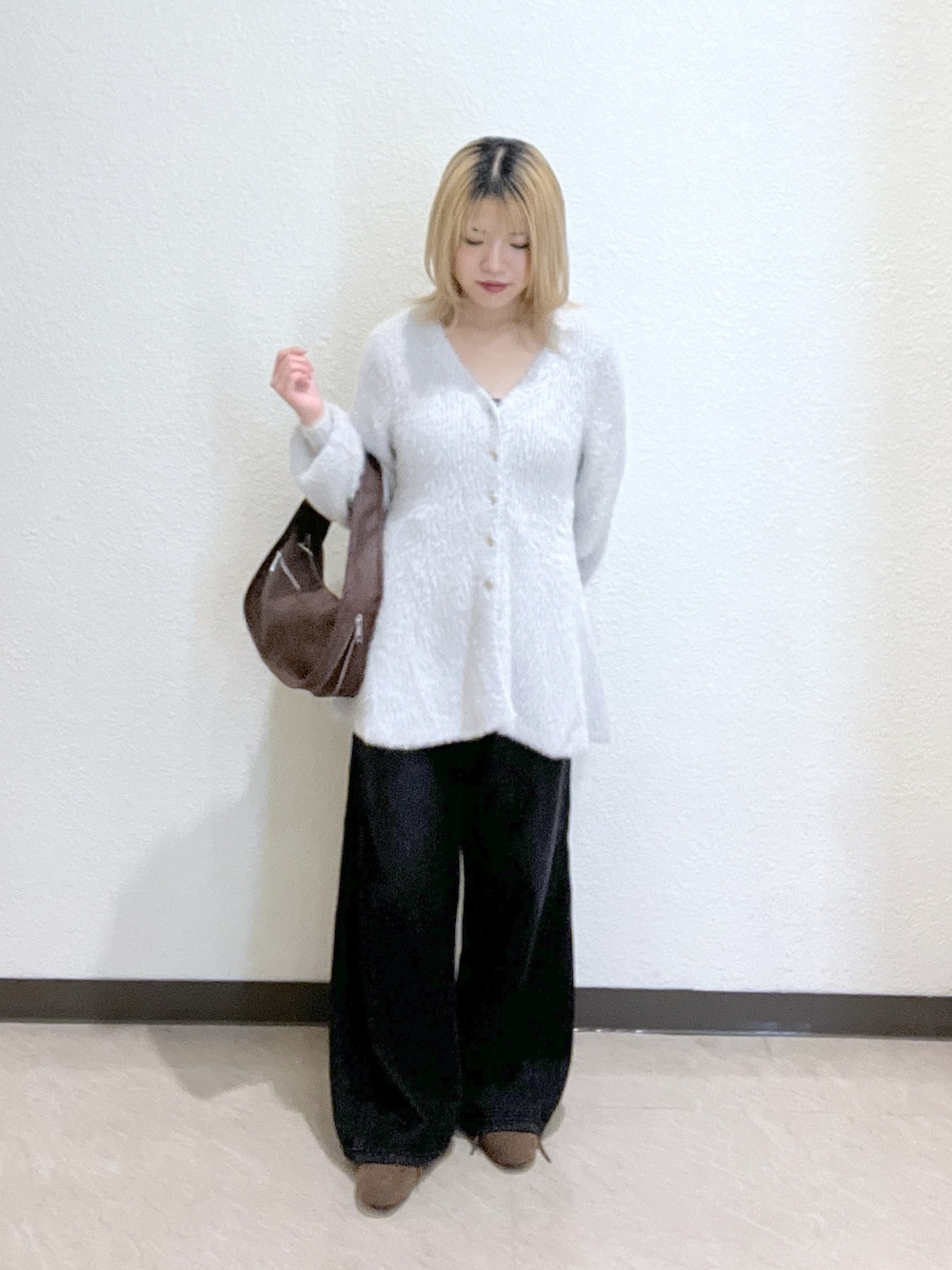 ブラウン系のハンドバッグ、グレー系のニット/セーター、ブラック系のデニムパンツを着用したレディースの秋コーディネートの1枚目の写真