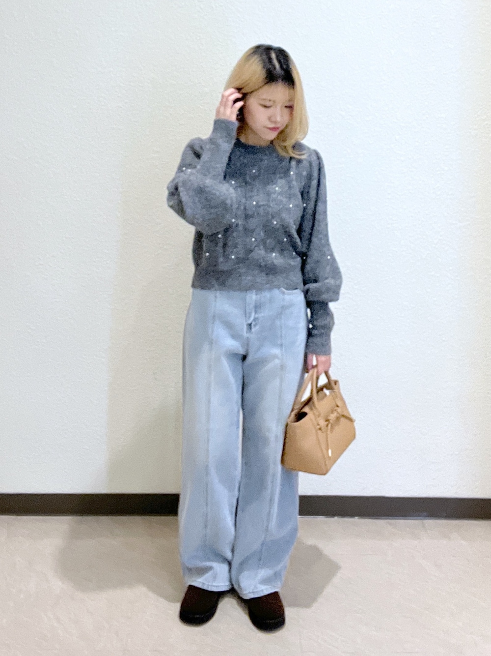 グレー系のニット/セーター、ブルー系のデニムパンツ、ベージュ系のトートバッグを着用したレディースの秋コーディネートの1枚目の写真