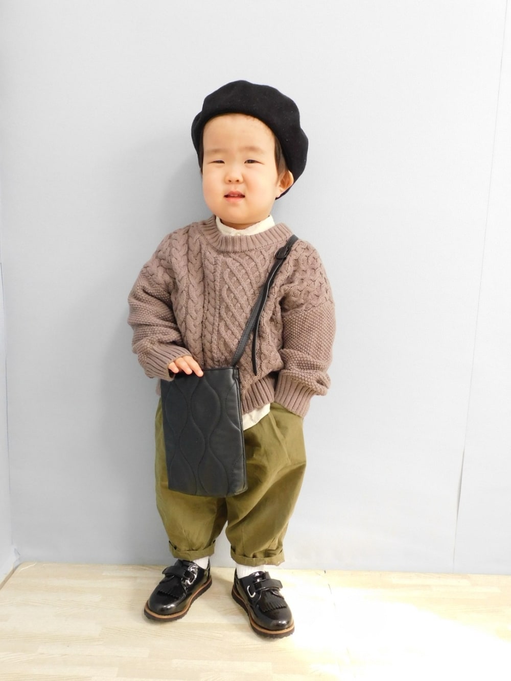 ホワイト系のシャツ/ブラウス、ブラウン系のニット/セーター、ブラック系のショルダーバッグを着用したキッズの冬コーディネートの2枚目の写真