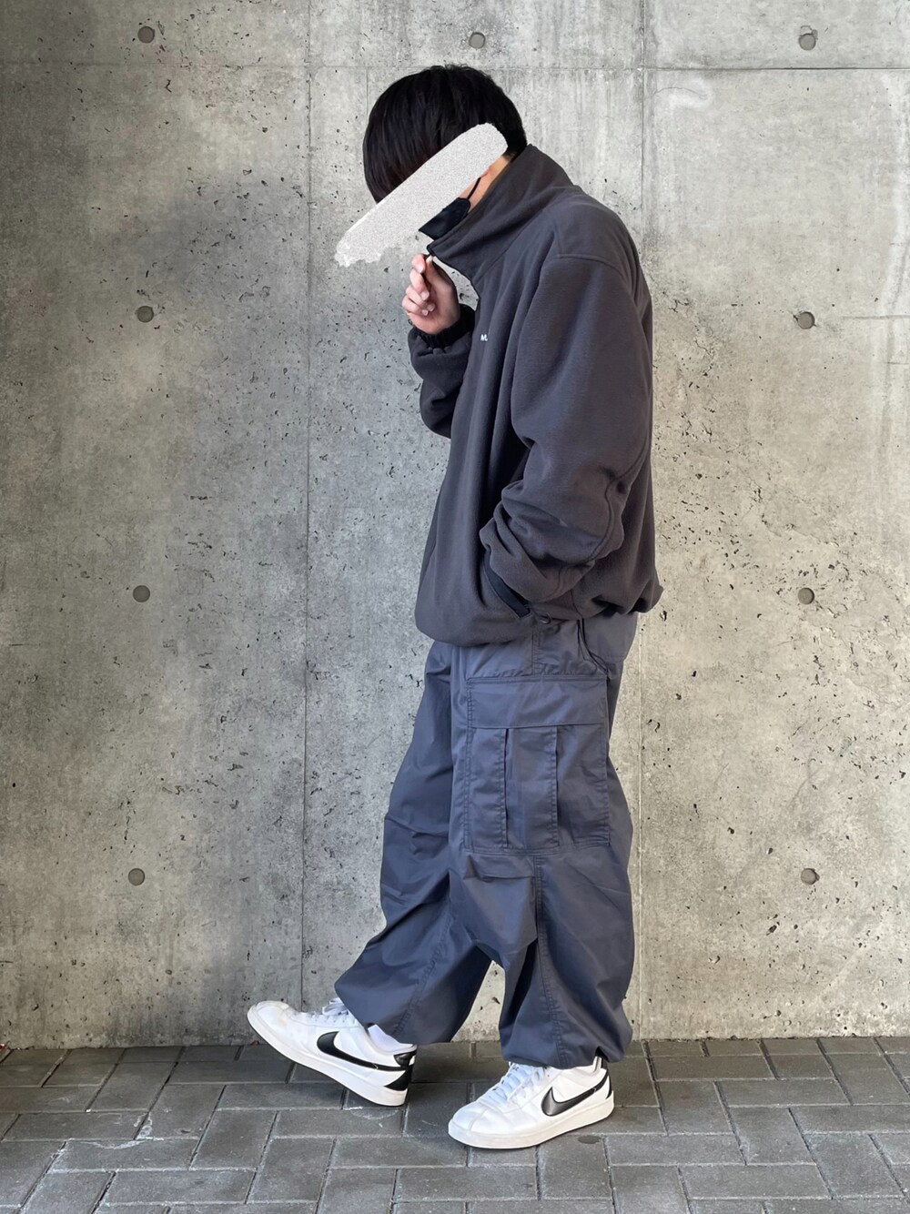 ブラック系のブルゾン、ブルー系のカーゴパンツ、ホワイト系のスニーカーを着用したメンズの冬コーディネートの1枚目の写真