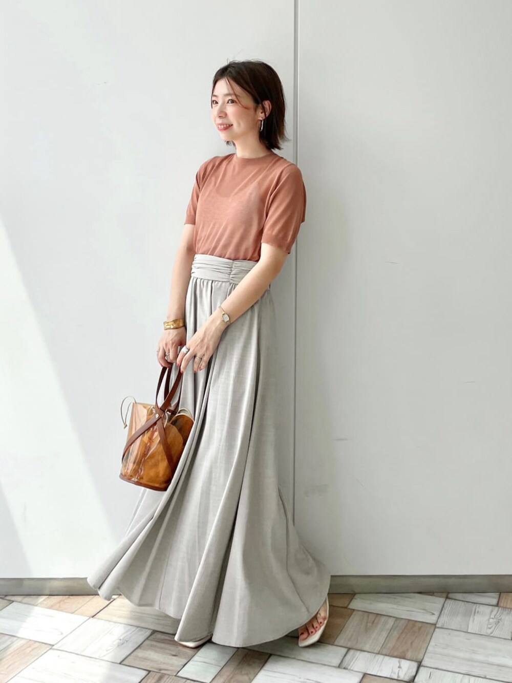 ブラウン系のニット/セーター、ベージュ系のスカート、イエロー系のショルダーバッグを着用したレディースの夏コーディネートの1枚目の写真