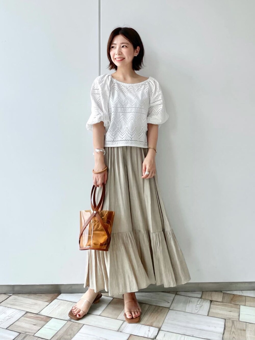 ホワイト系のシャツ/ブラウス、ベージュ系のスカート、イエロー系のショルダーバッグを着用したレディースの夏コーディネートの1枚目の写真
