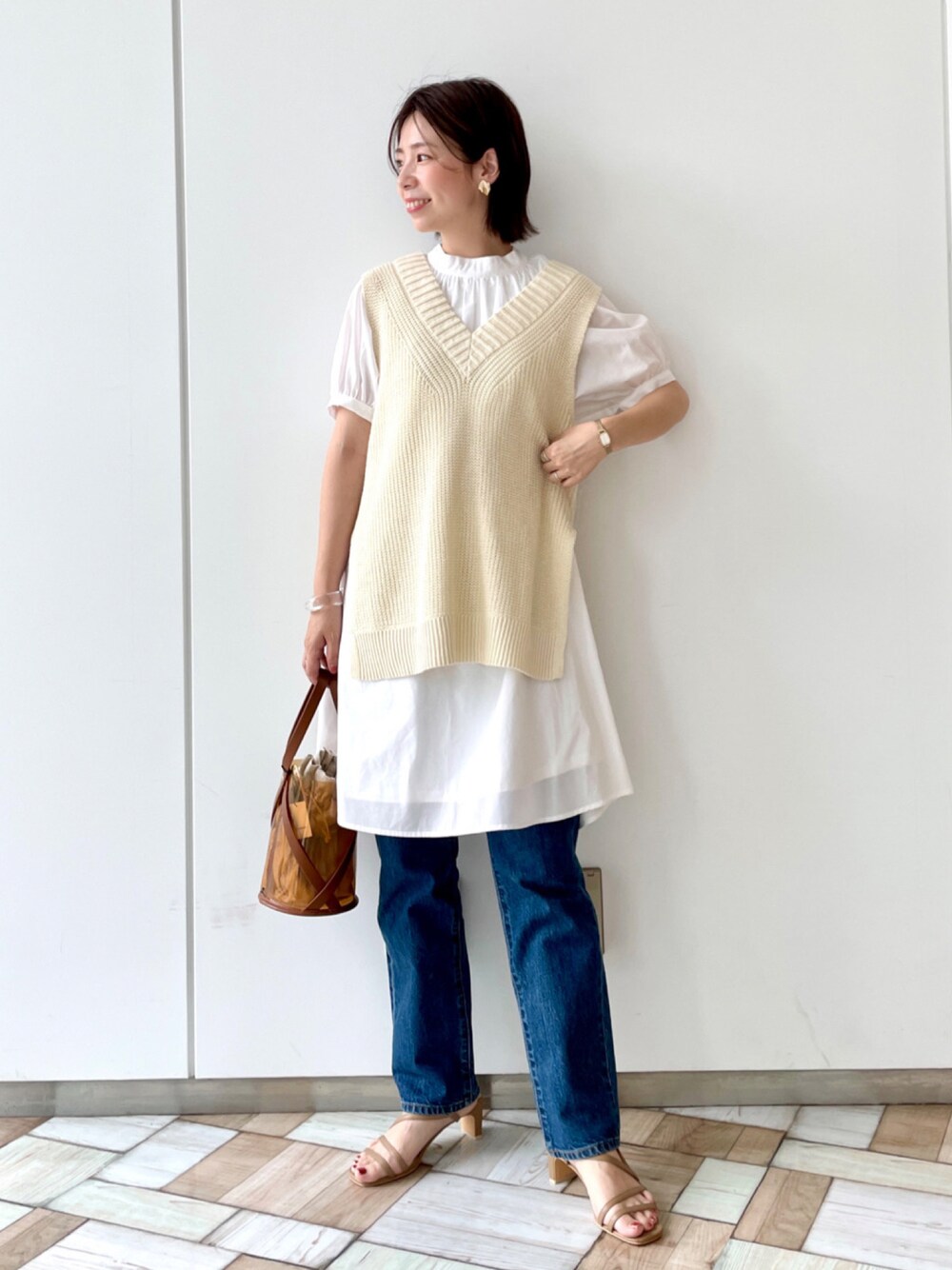 ブルー系のトップス、イエロー系のショルダーバッグ、ブルー系のデニムパンツを着用したレディースの夏コーディネートの1枚目の写真