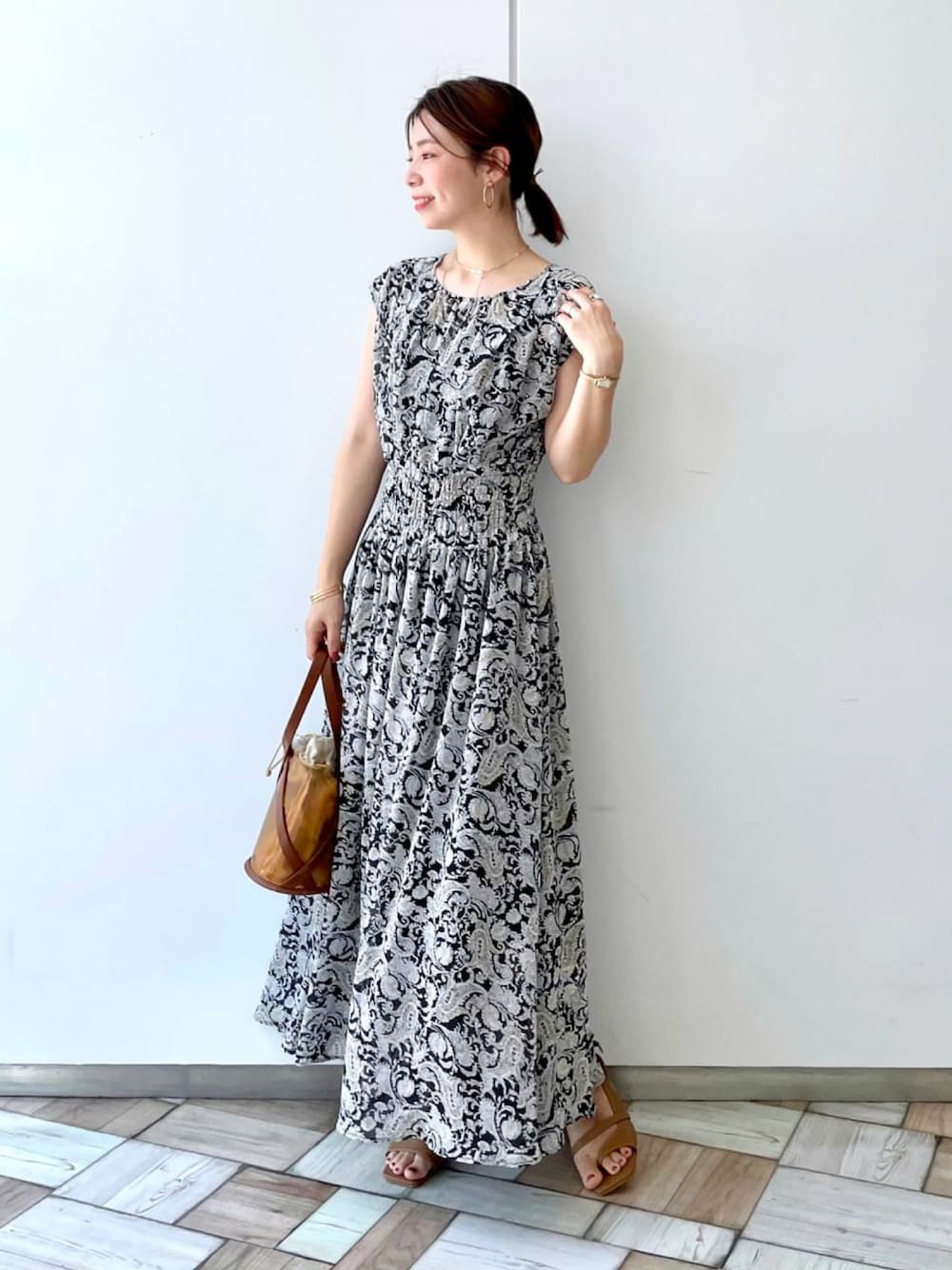 ベージュ系のワンピース、イエロー系のショルダーバッグを着用したレディースの夏コーディネートの1枚目の写真