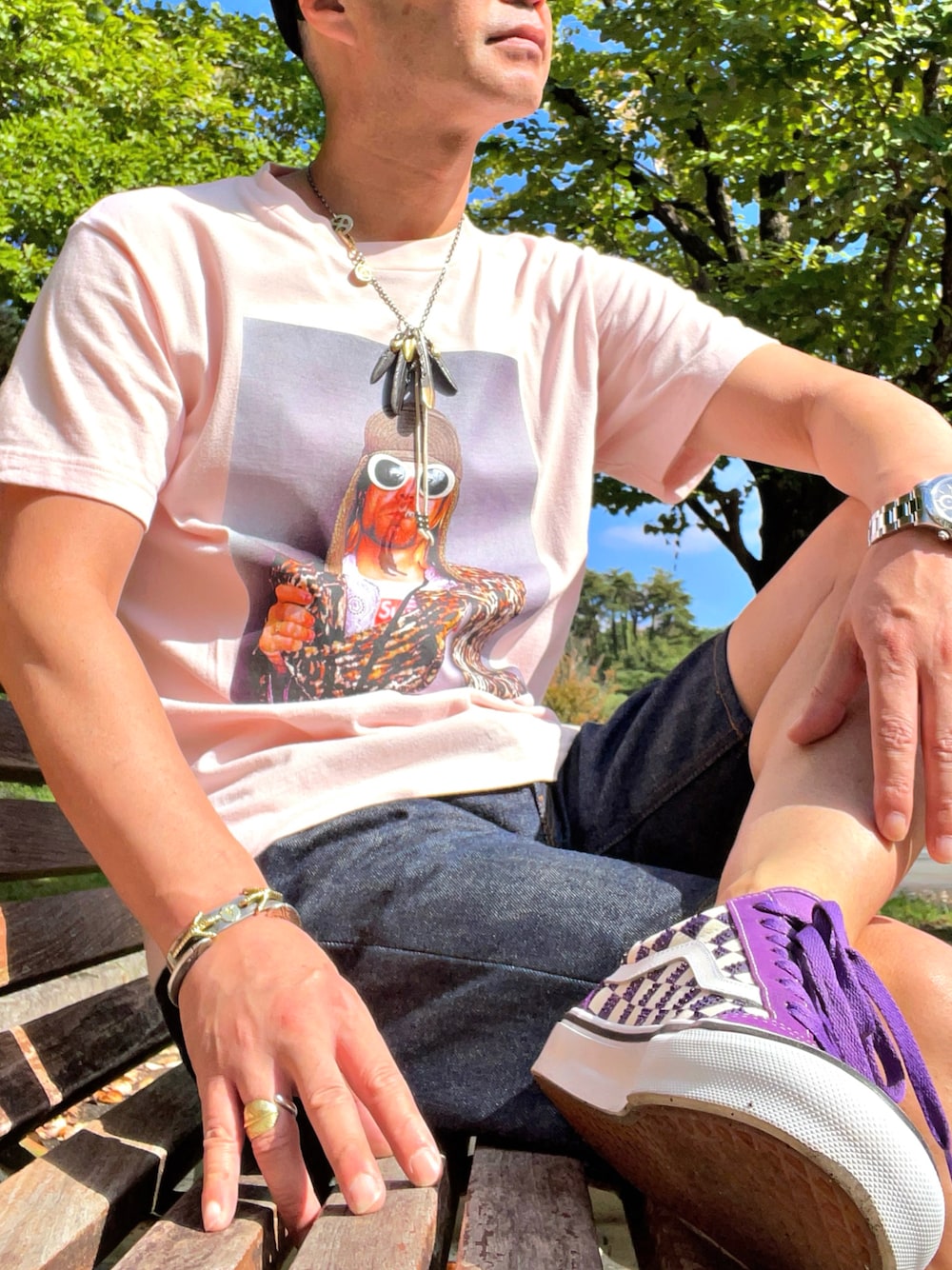 ピンク系のTシャツ/カットソー、パープル系のスニーカー、ブルー系のデニムパンツを着用したメンズの秋コーディネートの1枚目の写真