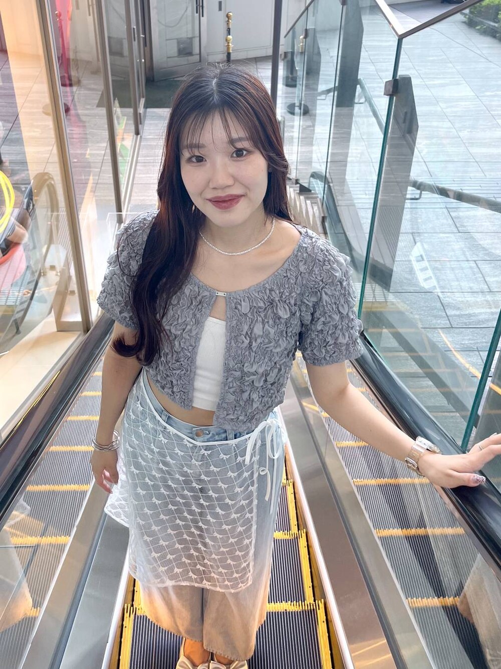 シルバー系のサンダル、ホワイト系のキャミソール、ブルー系のデニムパンツを着用したレディースの夏コーディネートの1枚目の写真