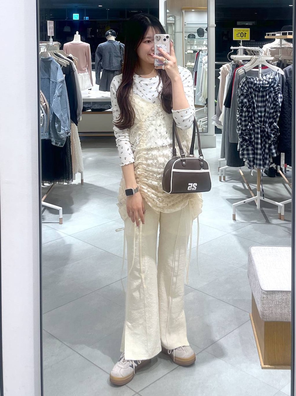 ベージュ系のワンピース、ブラウン系のボストンバッグ、ホワイト系のスマホグッズを着用したレディースの春コーディネートの1枚目の写真