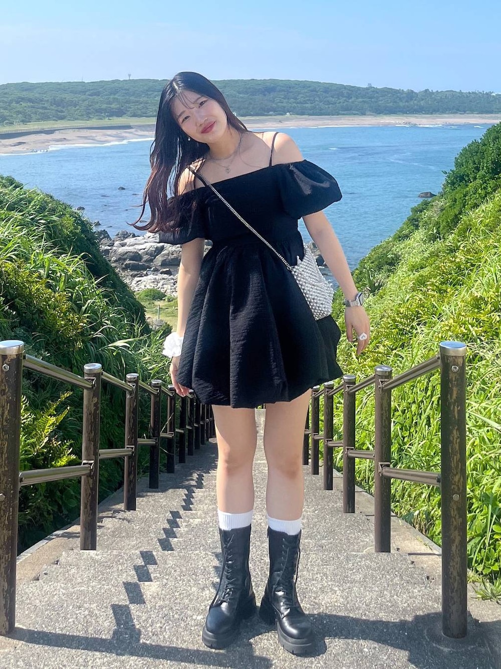 ホワイト系のキャミソール、ブラック系のワンピース、ブラック系のブーツを着用したレディースの夏コーディネートの1枚目の写真