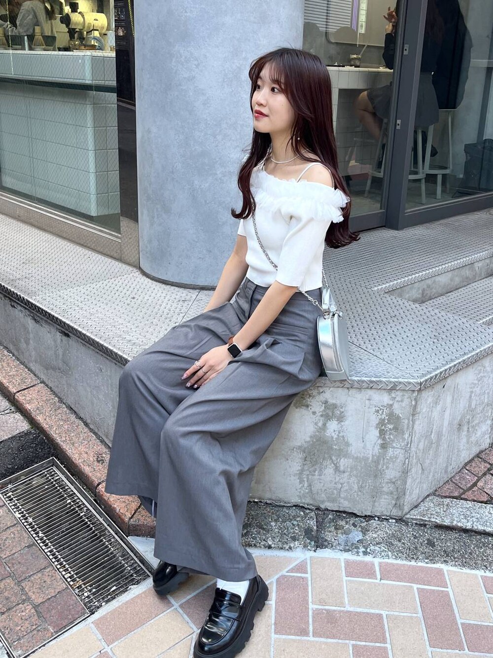 シルバー系のショルダーバッグ、ブラック系のローファー、グレー系のスラックスを着用したレディースの春コーディネートの1枚目の写真