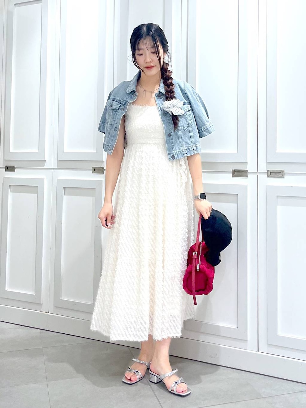 シルバー系のサンダル、ブルー系のデニムジャケット、ホワイト系のワンピースを着用したレディースの春コーディネートの1枚目の写真
