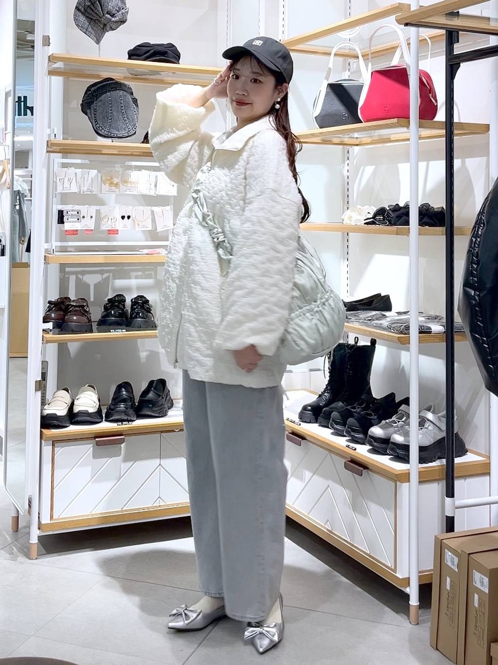 ブルー系のデニムパンツ、グリーン系のショルダーバッグ、シルバー系のパンプスを着用したレディースの春コーディネートの1枚目の写真