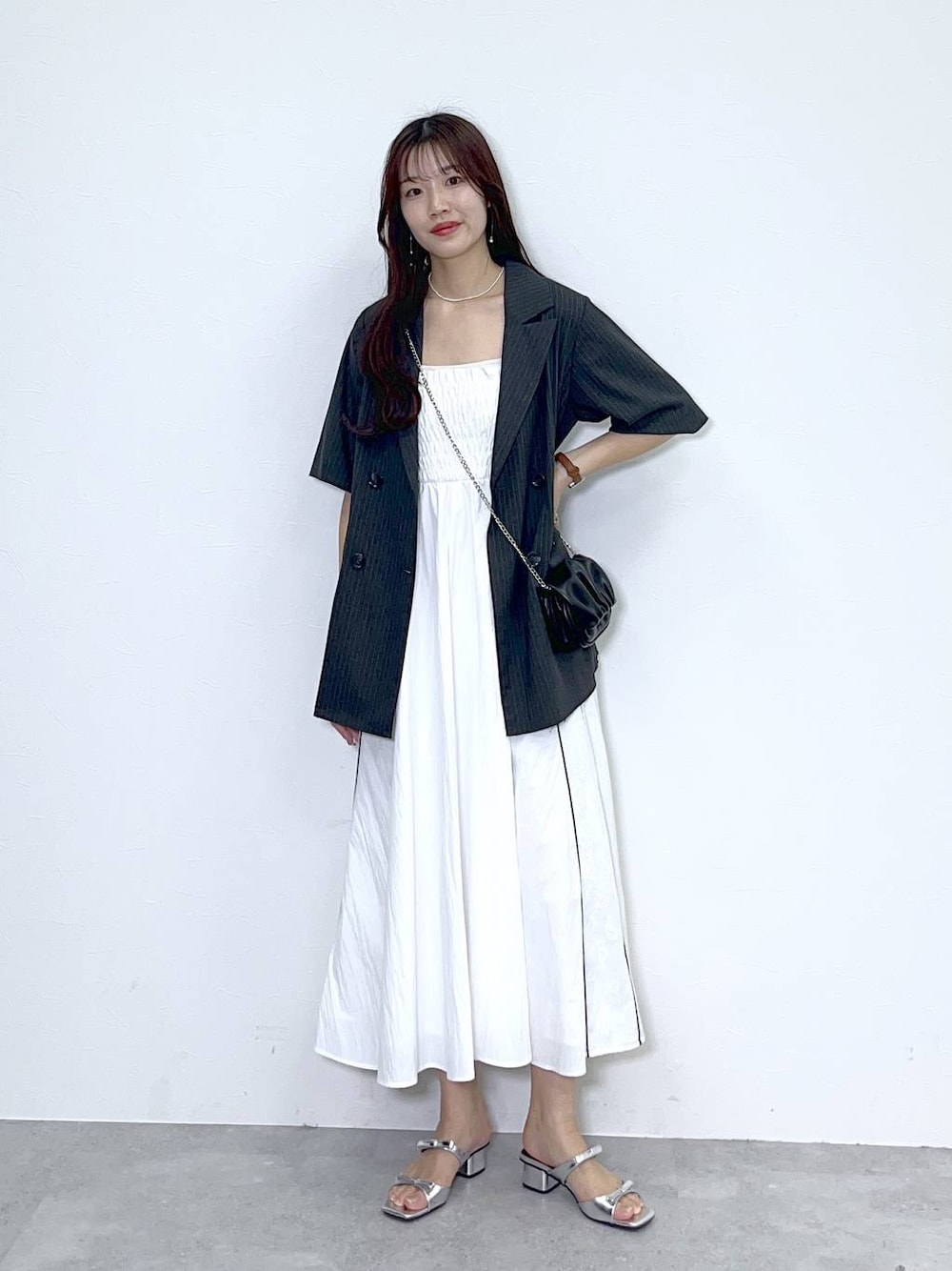 ブラック系のショルダーバッグ、シルバー系のサンダル、ホワイト系のワンピースを着用したレディースの春コーディネートの1枚目の写真