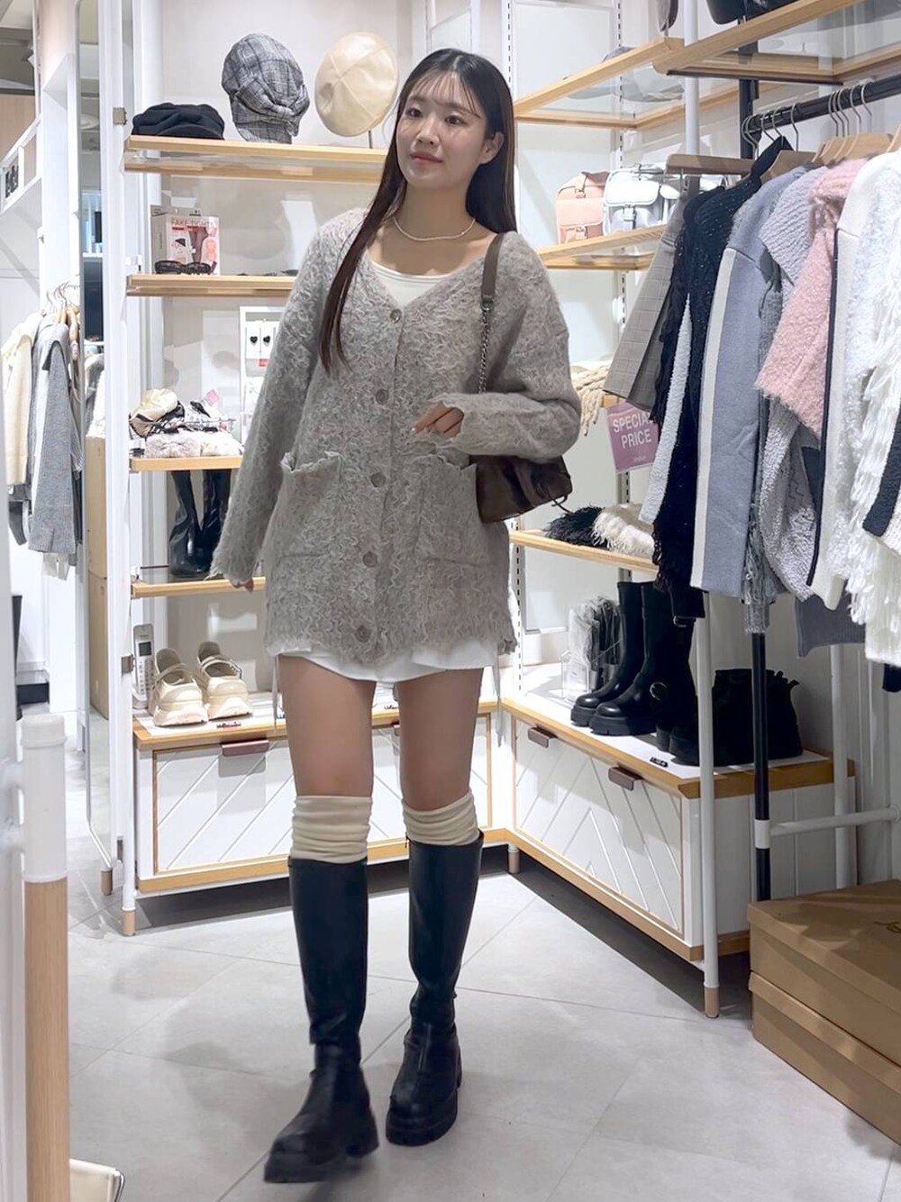 ブラウン系のショルダーバッグ、ホワイト系のTシャツ/カットソー、ブラック系のブーツを着用したレディースの冬コーディネートの1枚目の写真