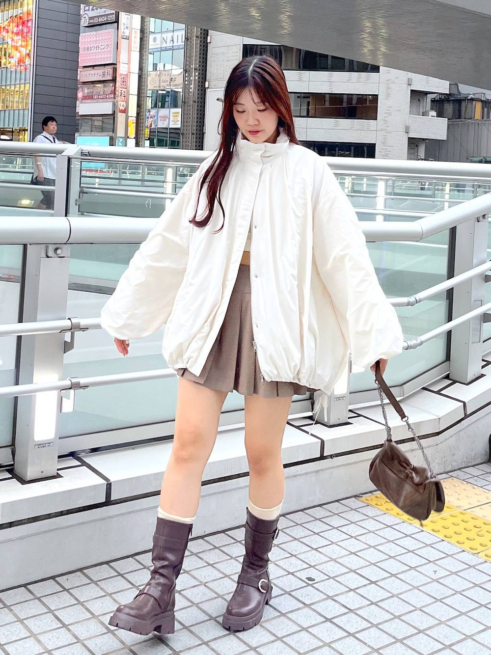 ブラウン系のショルダーバッグ、ブラウン系のブーツ、ホワイト系のキャミソールを着用したレディースの秋コーディネートの1枚目の写真