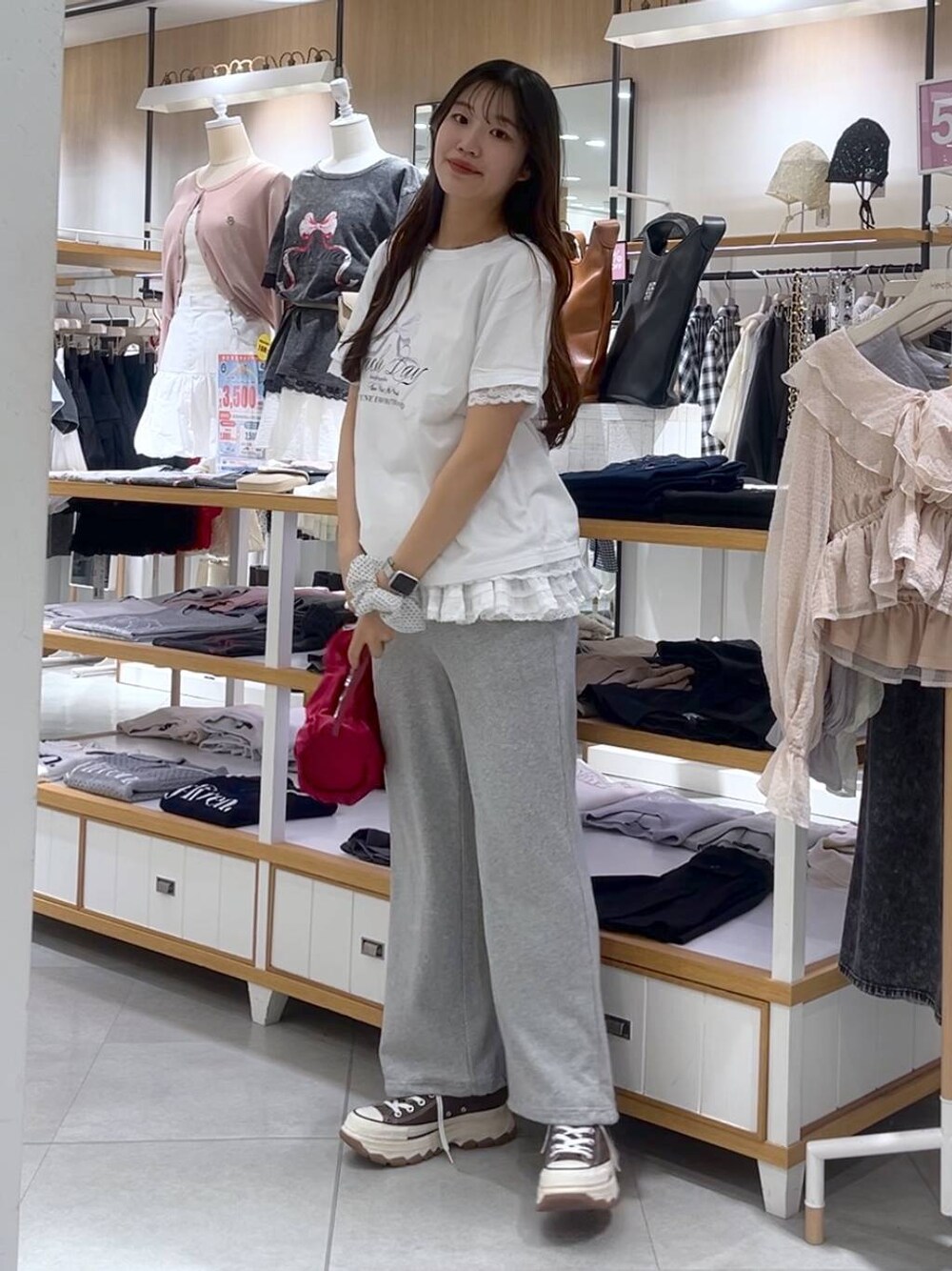 ホワイト系のキャミソール、レッド系のショルダーバッグ、グレー系のスウェットパンツを着用したレディースの春コーディネートの1枚目の写真