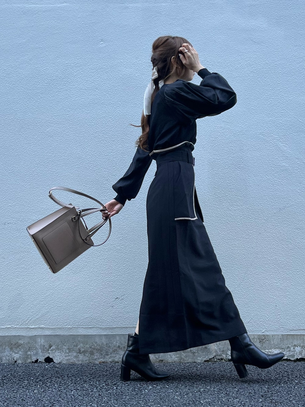 ブラック系のスカート、ベージュ系のバッグ、ブラック系のニット/セーターを着用したレディースの秋コーディネートの1枚目の写真