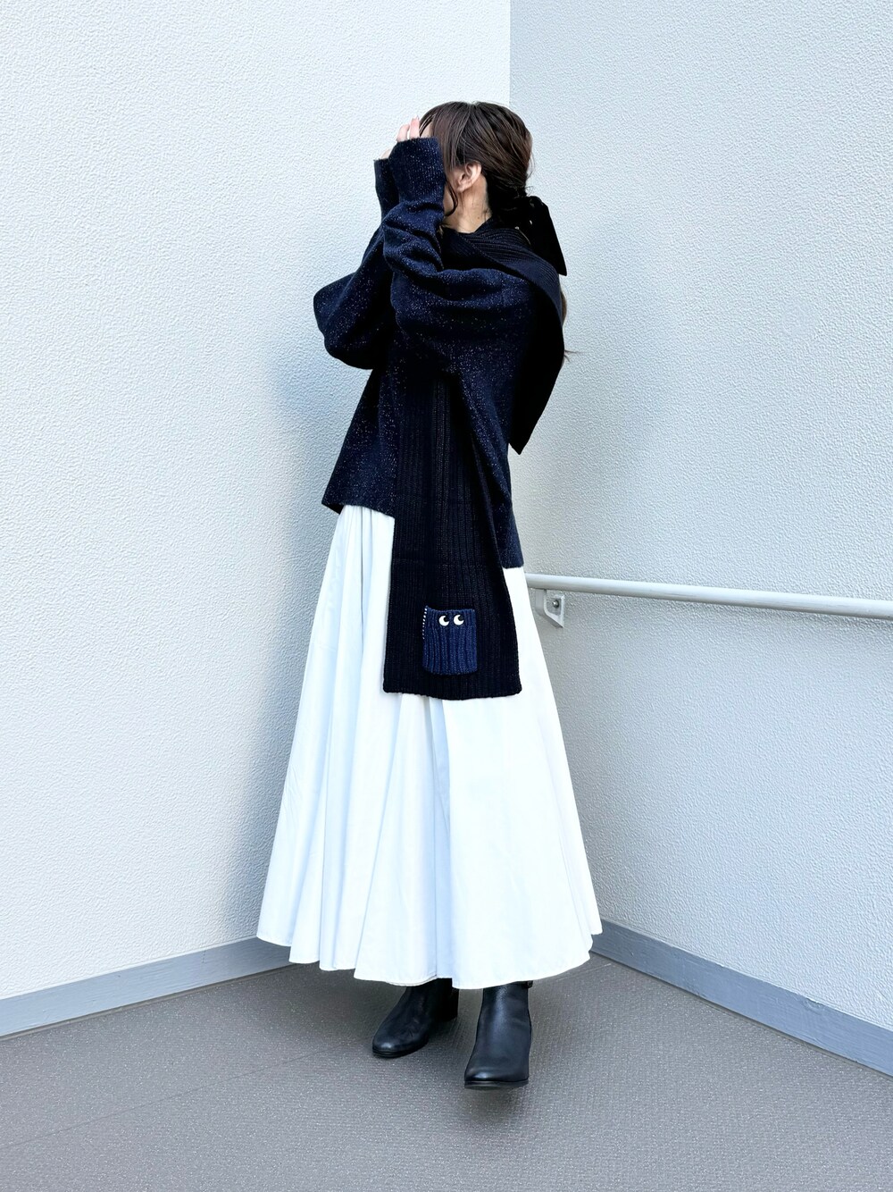 ブラック系のブーツ、ブルー系のニット/セーター、ホワイト系のスカートを着用したレディースの冬コーディネートの1枚目の写真