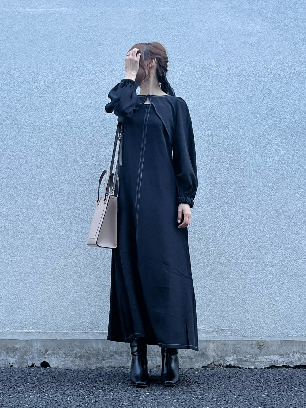 ブラック系のワンピース、ベージュ系のバッグ、ブラック系のブーツを着用したレディースの秋コーディネートの1枚目の写真