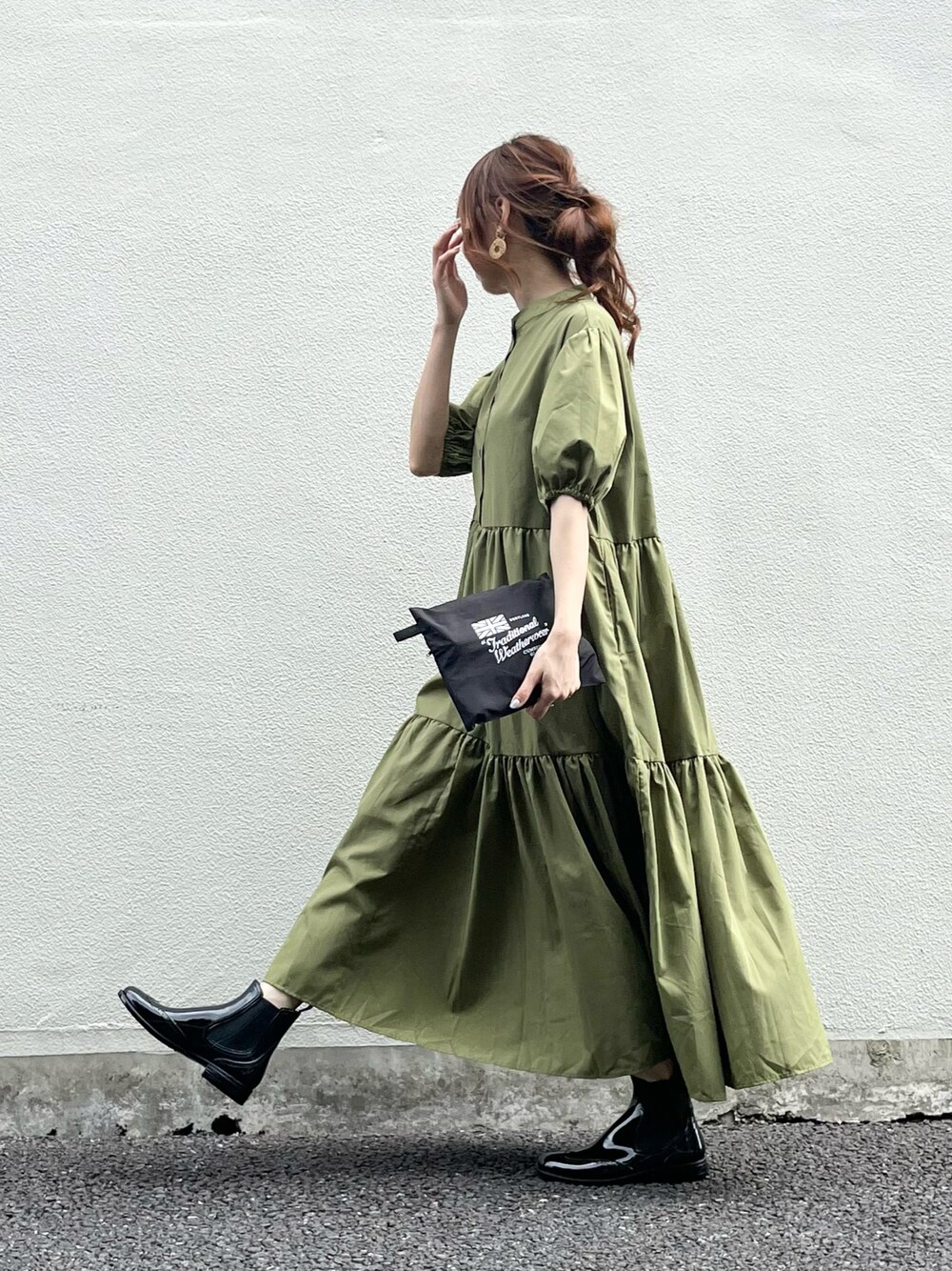 ブラック系のレインシューズ、グリーン系のワンピース、ブラック系のレインコート/ポンチョを着用したレディースの春コーディネートの1枚目の写真