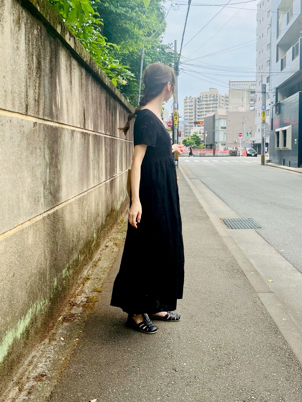 ブラック系のワンピース、ベージュ系のトートバッグ、グレー系のスマホグッズを着用したレディースの夏コーディネートの1枚目の写真