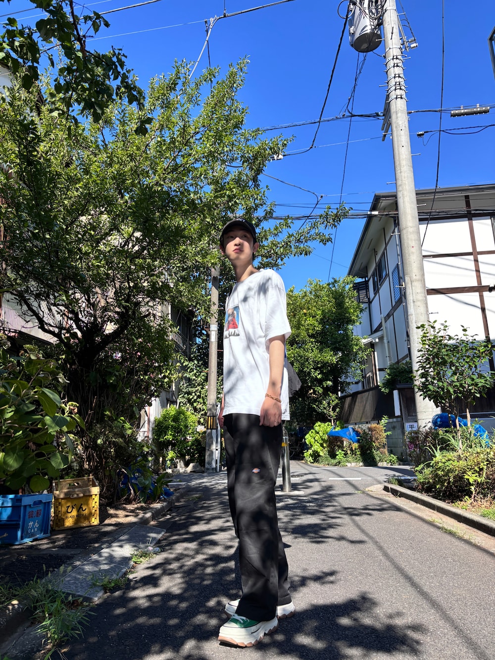 ブラック系のチノパンツ、グリーン系のスニーカー、ホワイト系のTシャツ/カットソーを着用したメンズの夏コーディネートの1枚目の写真