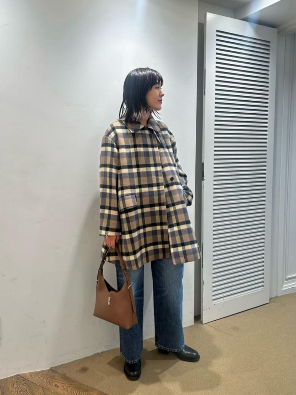 ブラック系のTシャツ/カットソー、ブラウン系のショルダーバッグ、ブラック系のブーツを着用したレディースの冬コーディネートの1枚目の写真