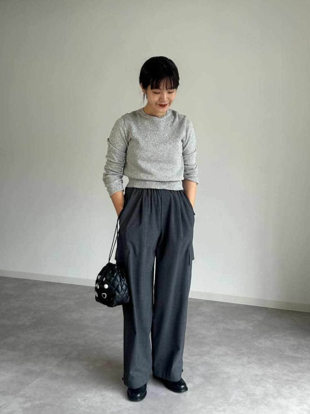 グレー系のニット/セーター、ブラック系のショルダーバッグを着用したレディースの秋コーディネートの1枚目の写真