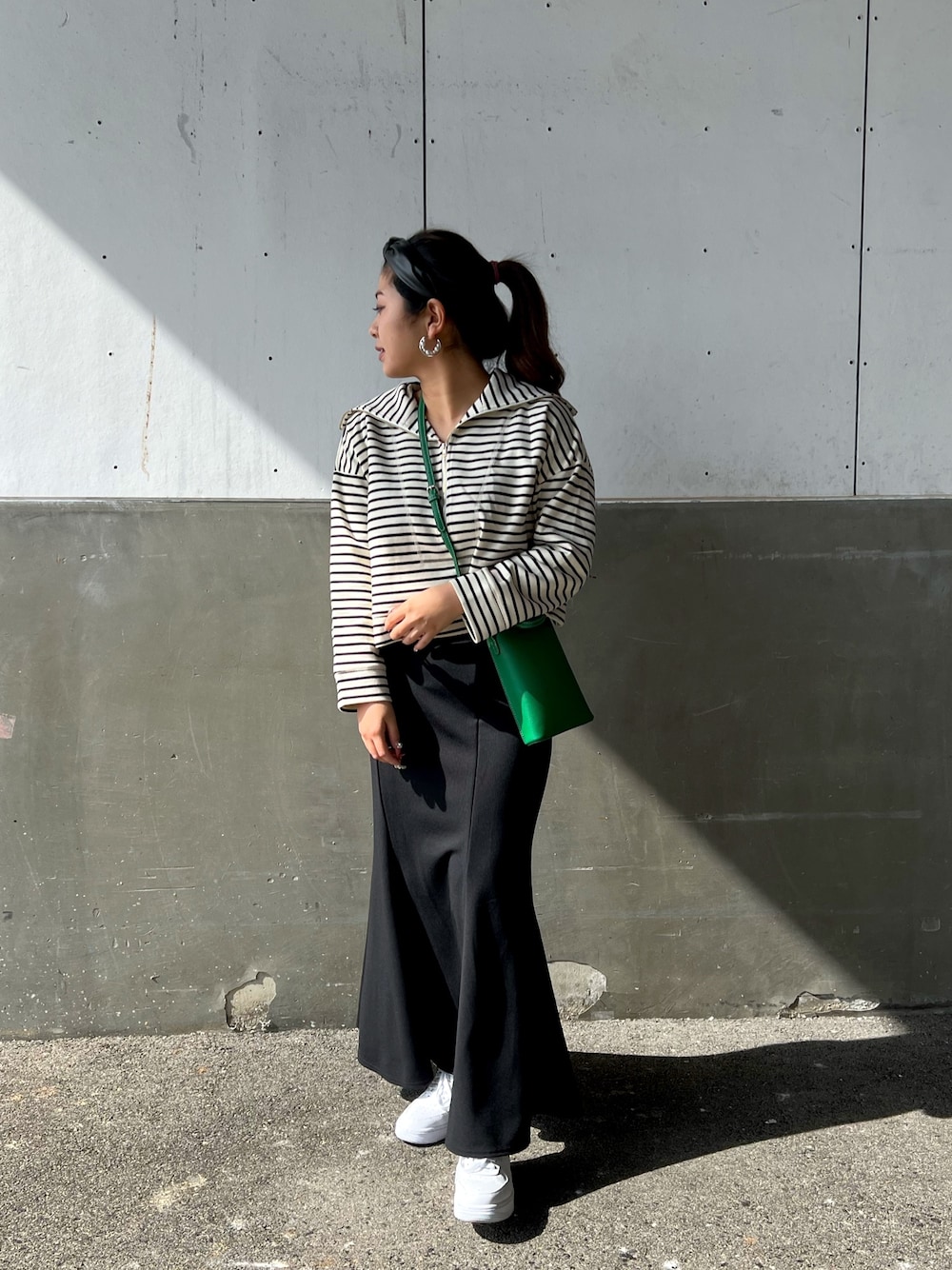 ホワイト系のTシャツ/カットソー、ブラック系のスカート、グリーン系のショルダーバッグを着用したレディースの冬コーディネートの2枚目の写真