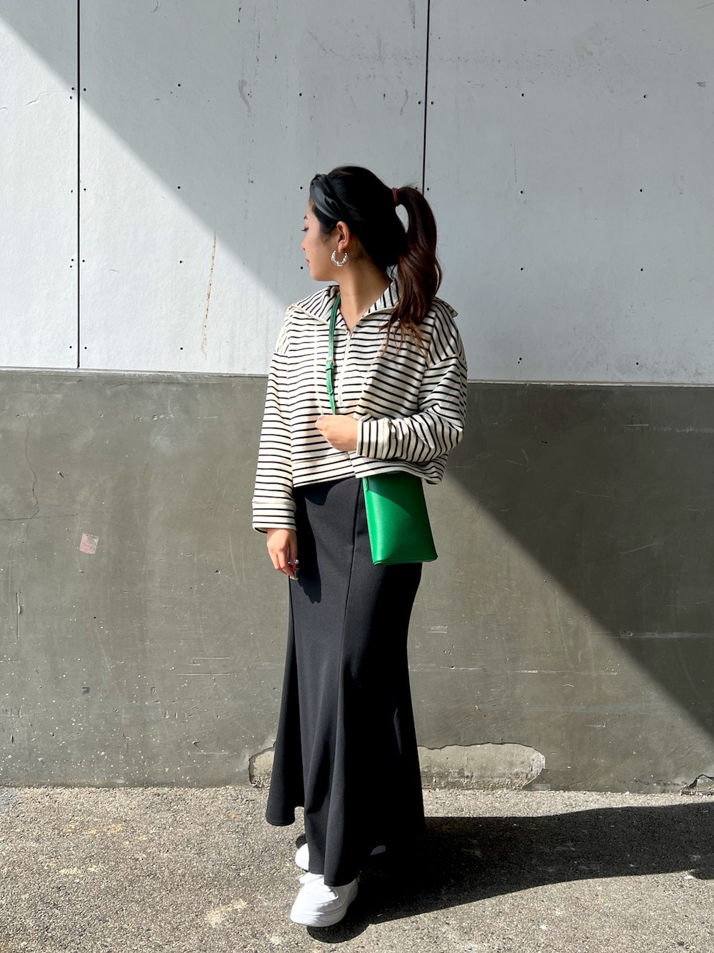 ホワイト系のTシャツ/カットソー、ブラック系のスカート、グリーン系のショルダーバッグを着用したレディースの冬コーディネートの3枚目の写真