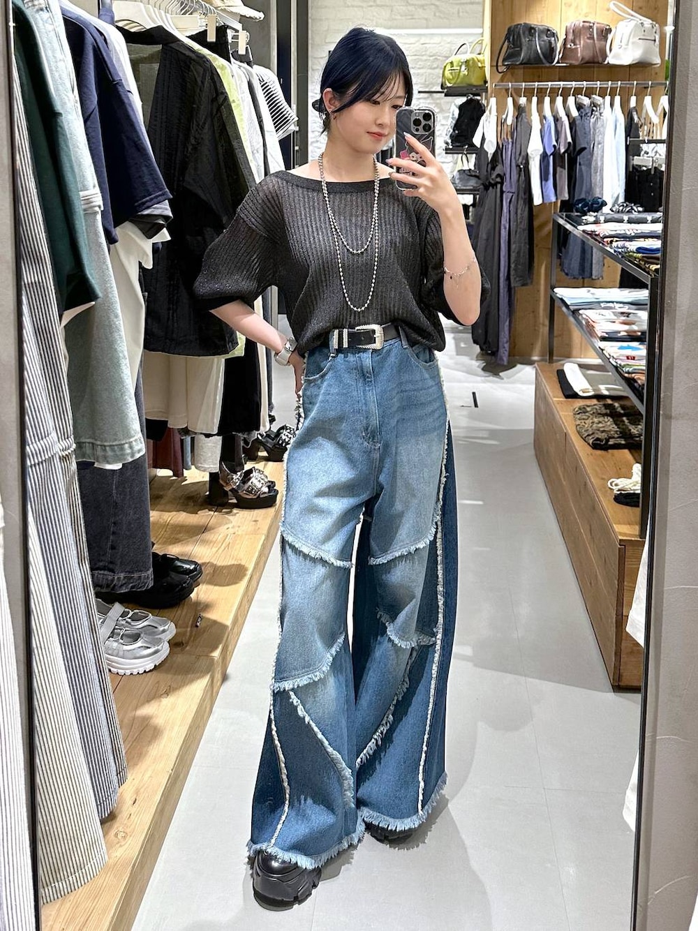 ブルー系のデニムパンツ、ブラック系のニット/セーター、ブラック系のベルトを着用したレディースの夏コーディネートの1枚目の写真