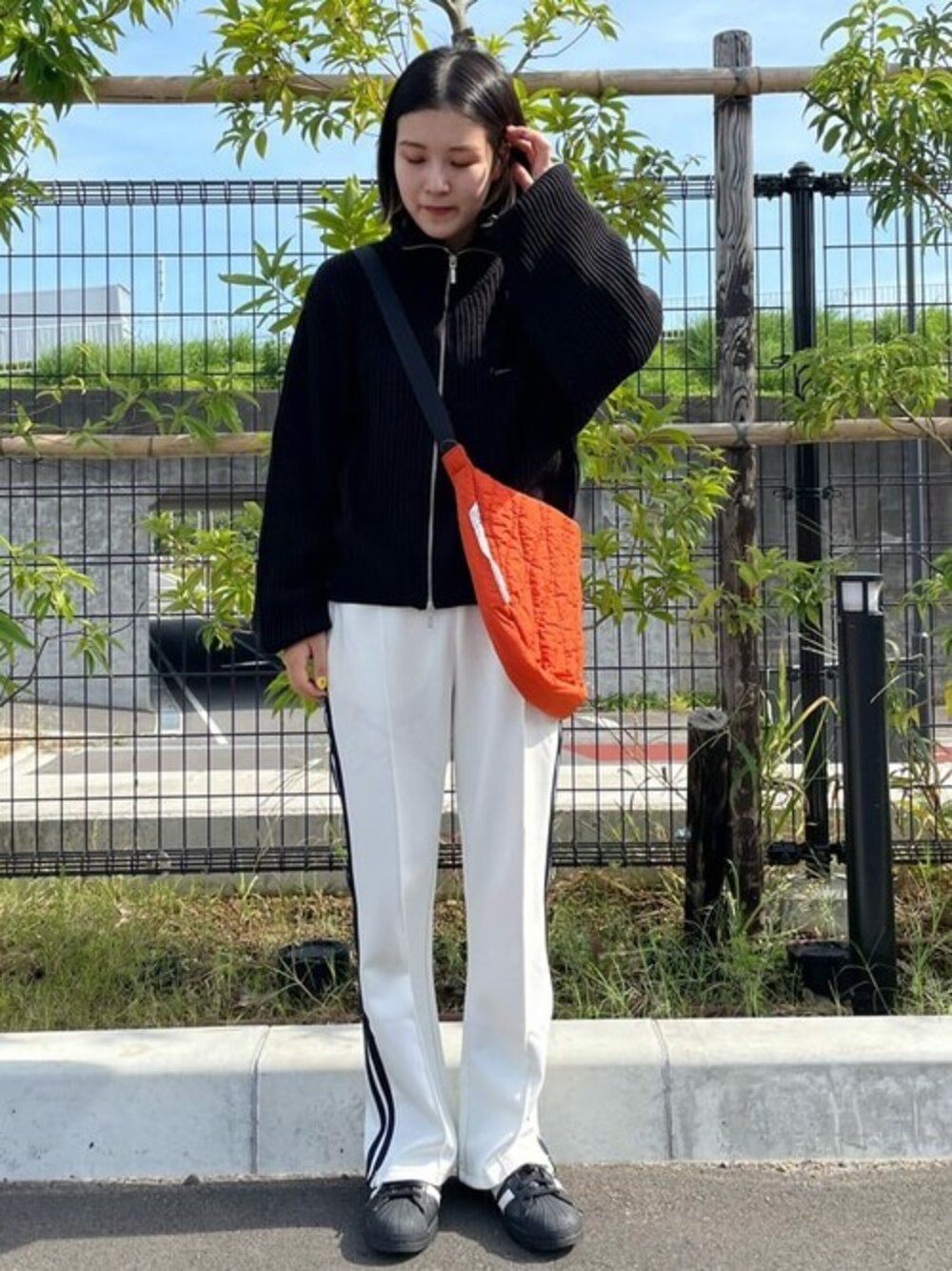 オレンジ系のショルダーバッグを着用したレディースの冬コーディネートの1枚目の写真