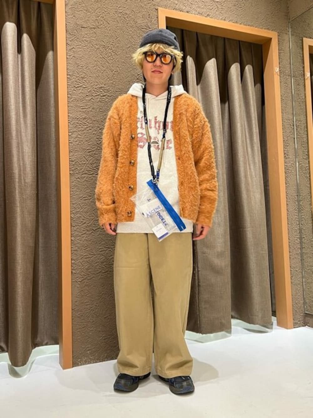 オレンジ系のカーディガン/ボレロ、グレー系のパーカー、ベージュ系のチノパンツを着用したメンズの冬コーディネートの1枚目の写真