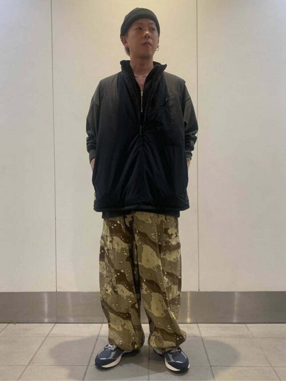 ブラック系のベスト、グレー系のスウェット、ブルー系のスニーカーを着用したメンズの冬コーディネートの1枚目の写真