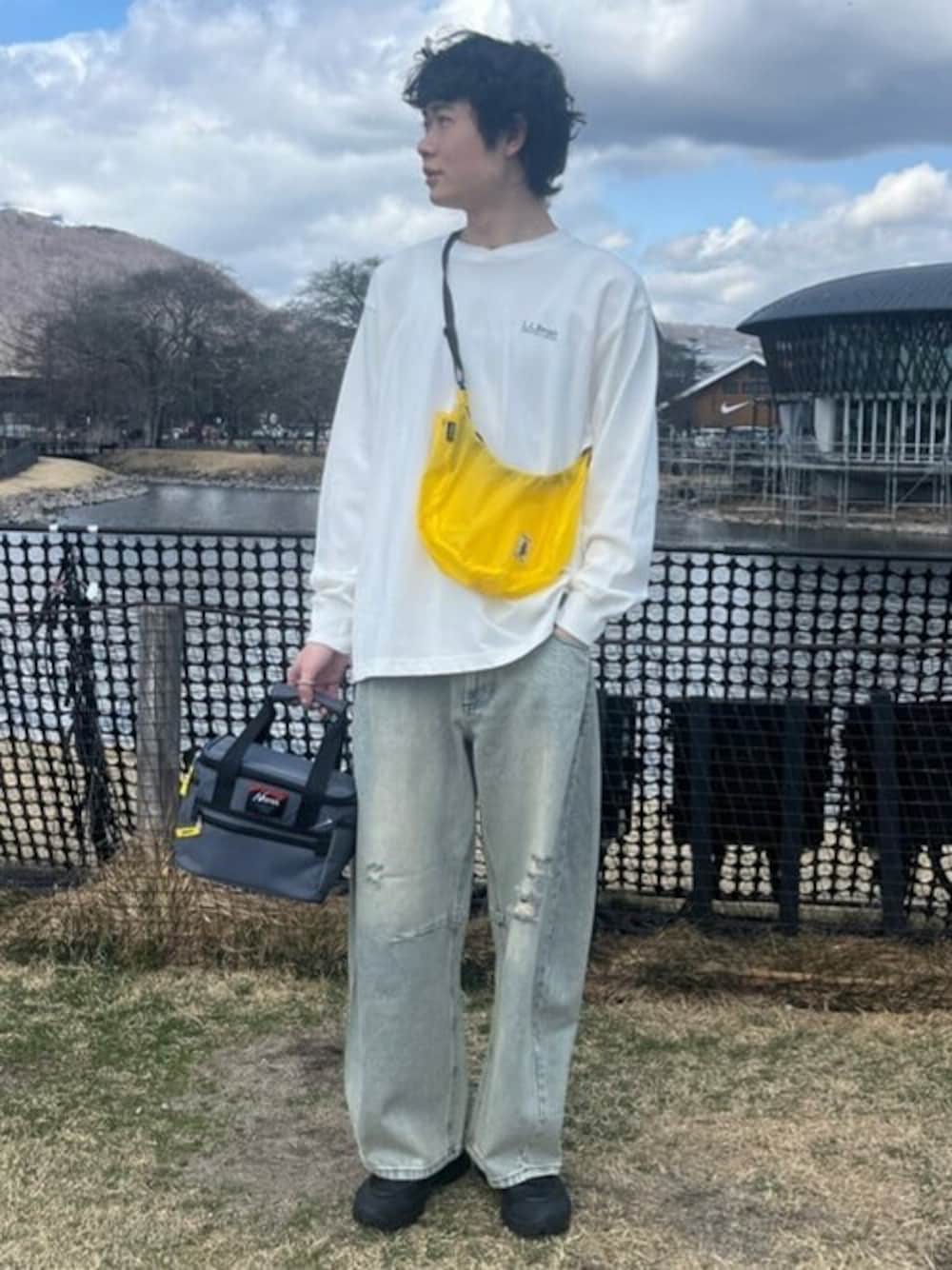 ブルー系のデニムパンツ、グレー系のアウトドアグッズを着用したメンズの春コーディネートの1枚目の写真