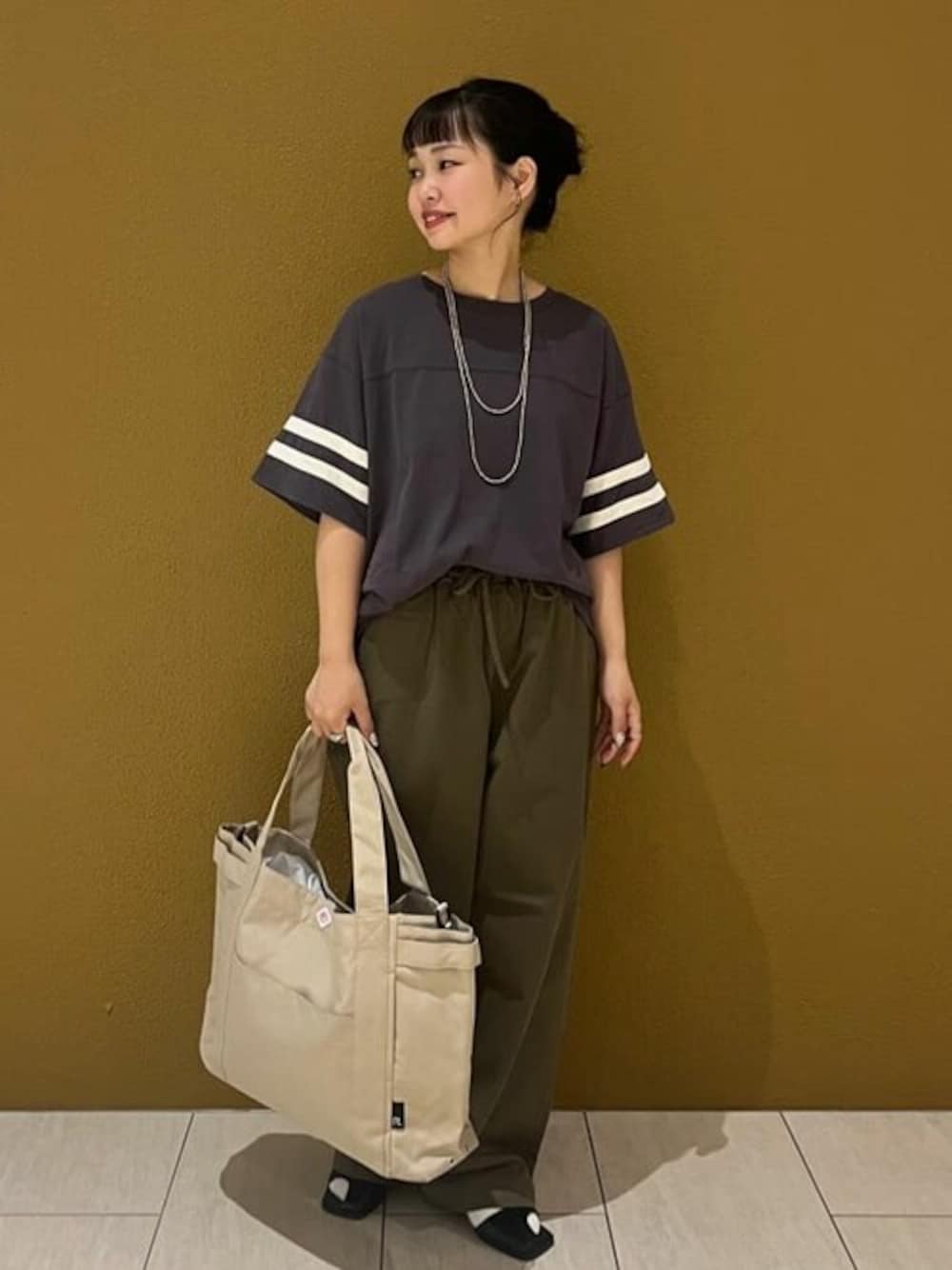 グレー系のTシャツ/カットソー、グリーン系のデニムパンツ、ベージュ系のトートバッグを着用したレディースの夏コーディネートの1枚目の写真