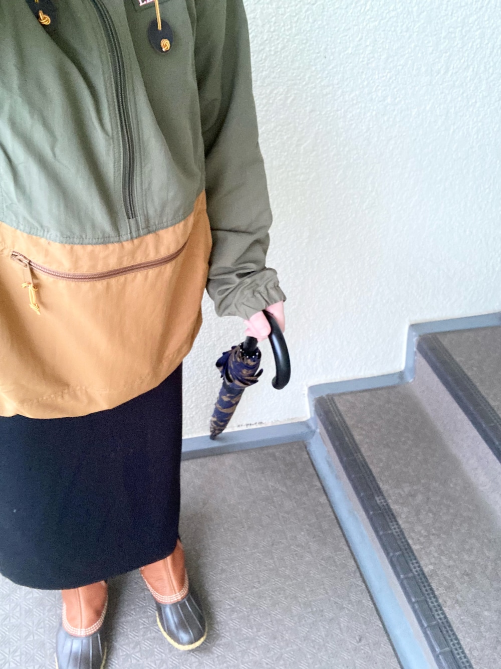 ブラウン系のブーツ、イエロー系のナイロンジャケット、グレー系のスカートを着用したレディースの冬コーディネートの1枚目の写真