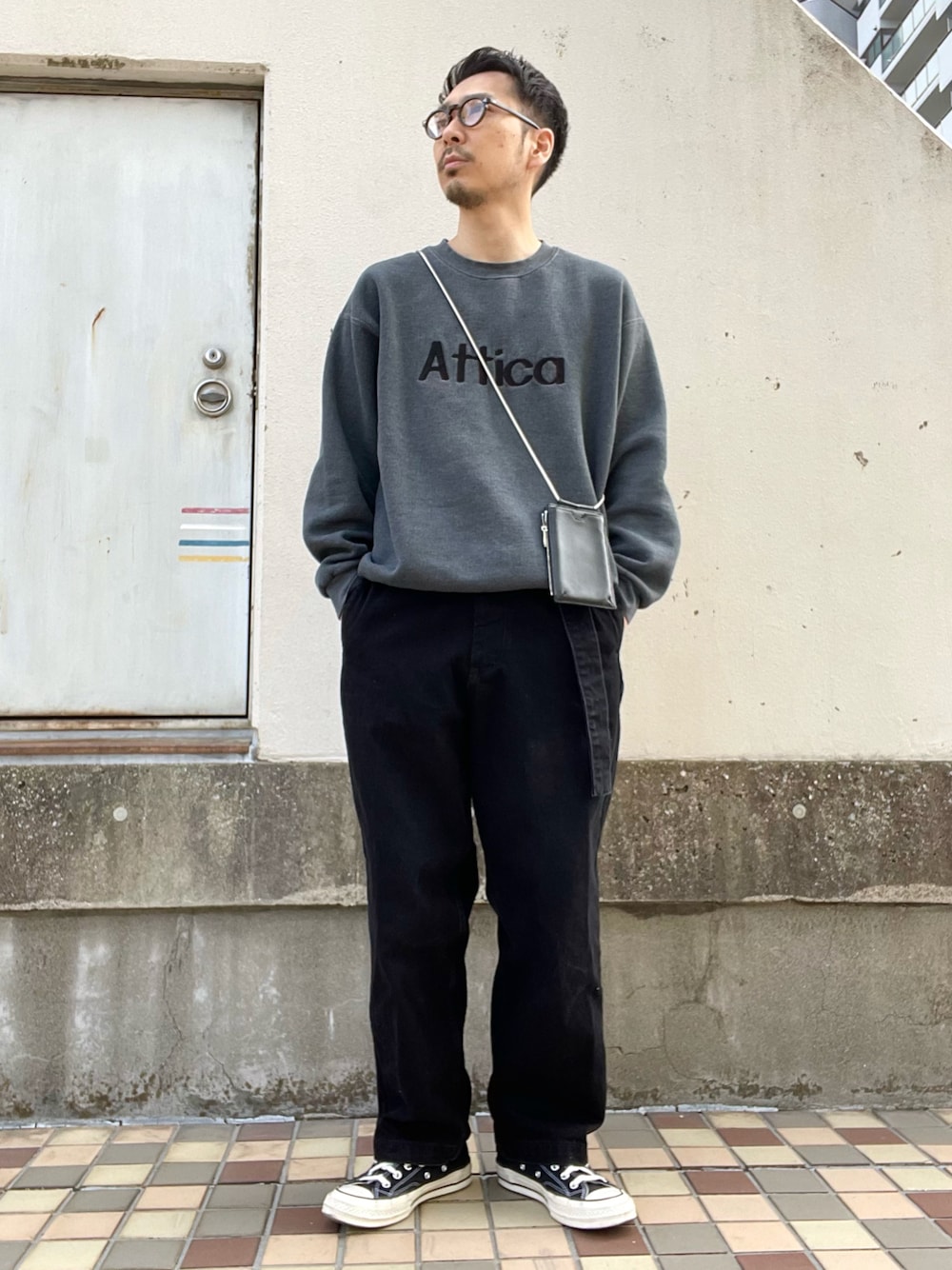 グレー系のスウェット、ブラック系のデニムパンツ、ブラック系のスニーカーを着用したメンズの春コーディネートの1枚目の写真