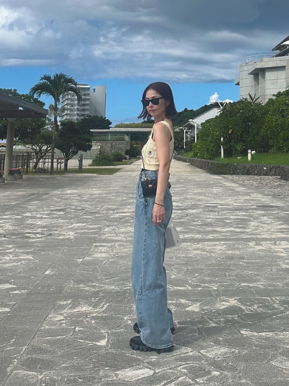 ブルー系のデニムパンツ、ブラック系のバッグ、ブラック系のスニーカーを着用したレディースの秋コーディネートの1枚目の写真