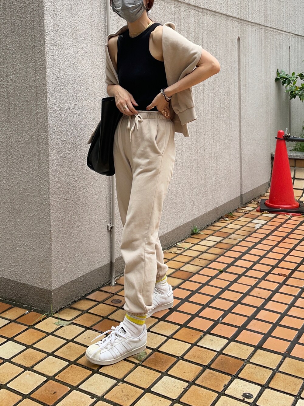 ベージュ系のスウェットパンツ、ブラック系のタンクトップ、ブラック系のトートバッグを着用したレディースの秋コーディネートの1枚目の写真