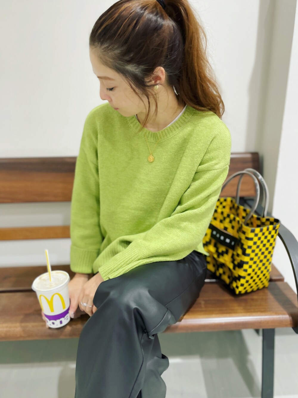 グリーン系のニット/セーター、ブラック系のスラックス、ゴールド系のイヤリングを着用したレディースの秋コーディネートの1枚目の写真