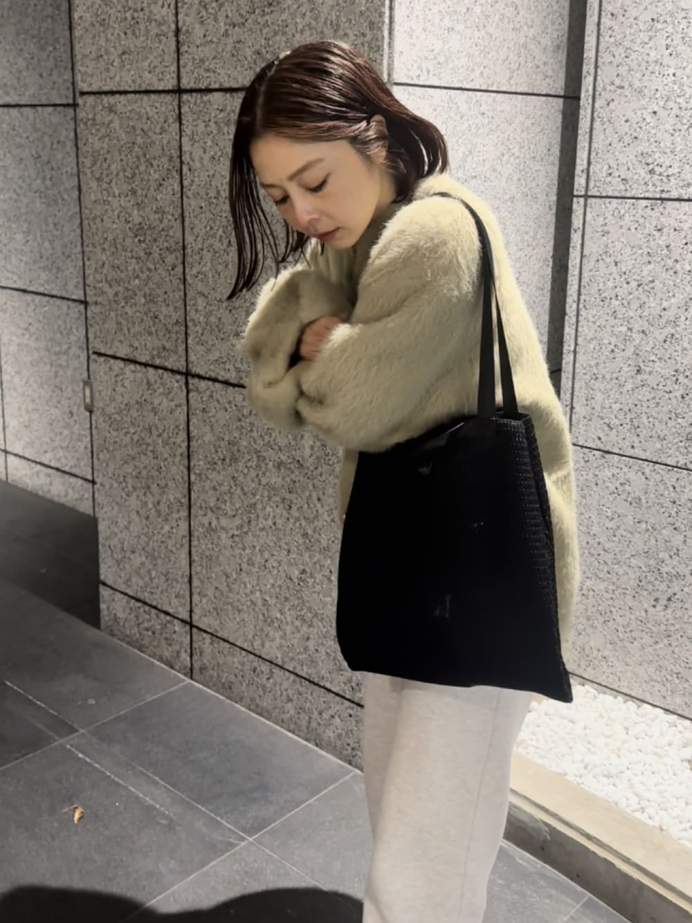 ブラック系のトートバッグ、ホワイト系のスウェットパンツを着用したレディースの冬コーディネートの1枚目の写真