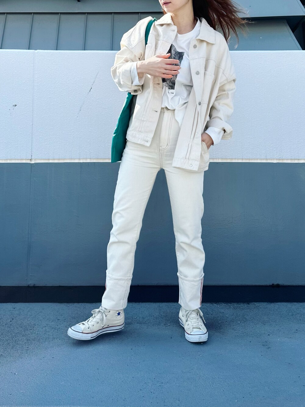 ブラック系のデニムジャケット、ブルー系のデニムパンツ、グリーン系のトートバッグを着用したレディースの冬コーディネートの1枚目の写真