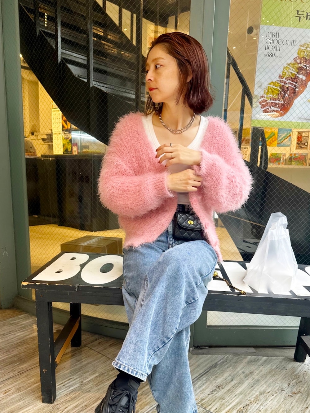 ピンク系のカーディガン/ボレロ、ブラック系のバッグを着用したレディースの秋コーディネートの1枚目の写真