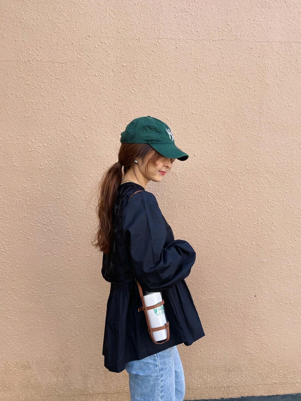 ブラック系のシャツ/ブラウス、グリーン系のキャップを着用したレディースの秋コーディネートの1枚目の写真