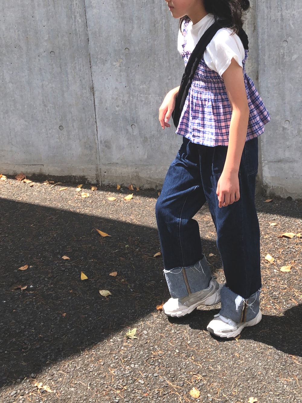 ブルー系のパンツ、ブラック系のショルダーバッグ、ホワイト系のスニーカーを着用したキッズの夏コーディネートの1枚目の写真