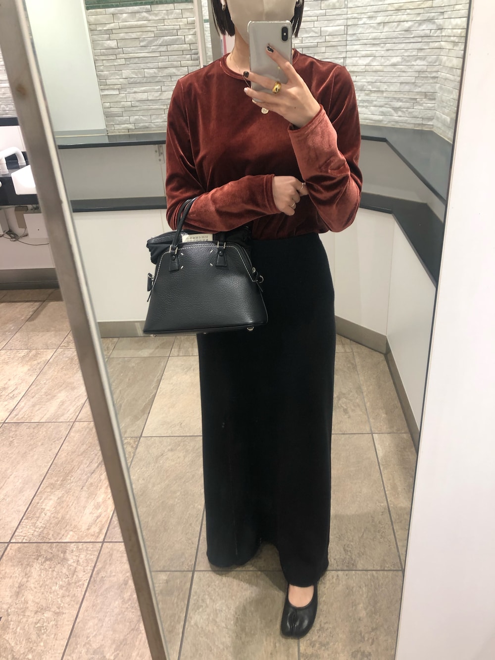 レッド系のTシャツ/カットソー、ブラック系のスカート、ブラック系のハンドバッグを着用したレディースの秋コーディネートの1枚目の写真
